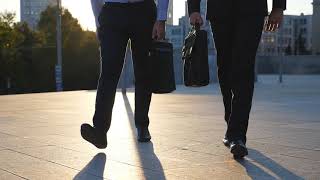 feet of two businessmen with briefcases walking ZYWBMCL