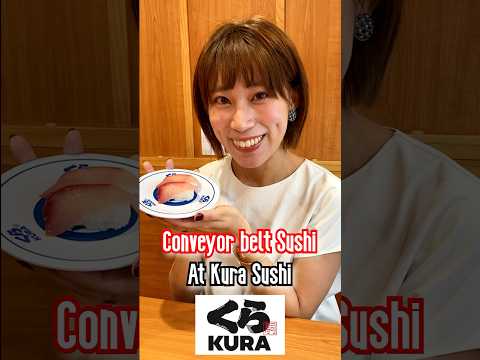 A Japanese girl shares Sushi at a Conveyor Belt Sushi Restaurant, Kura Sushi